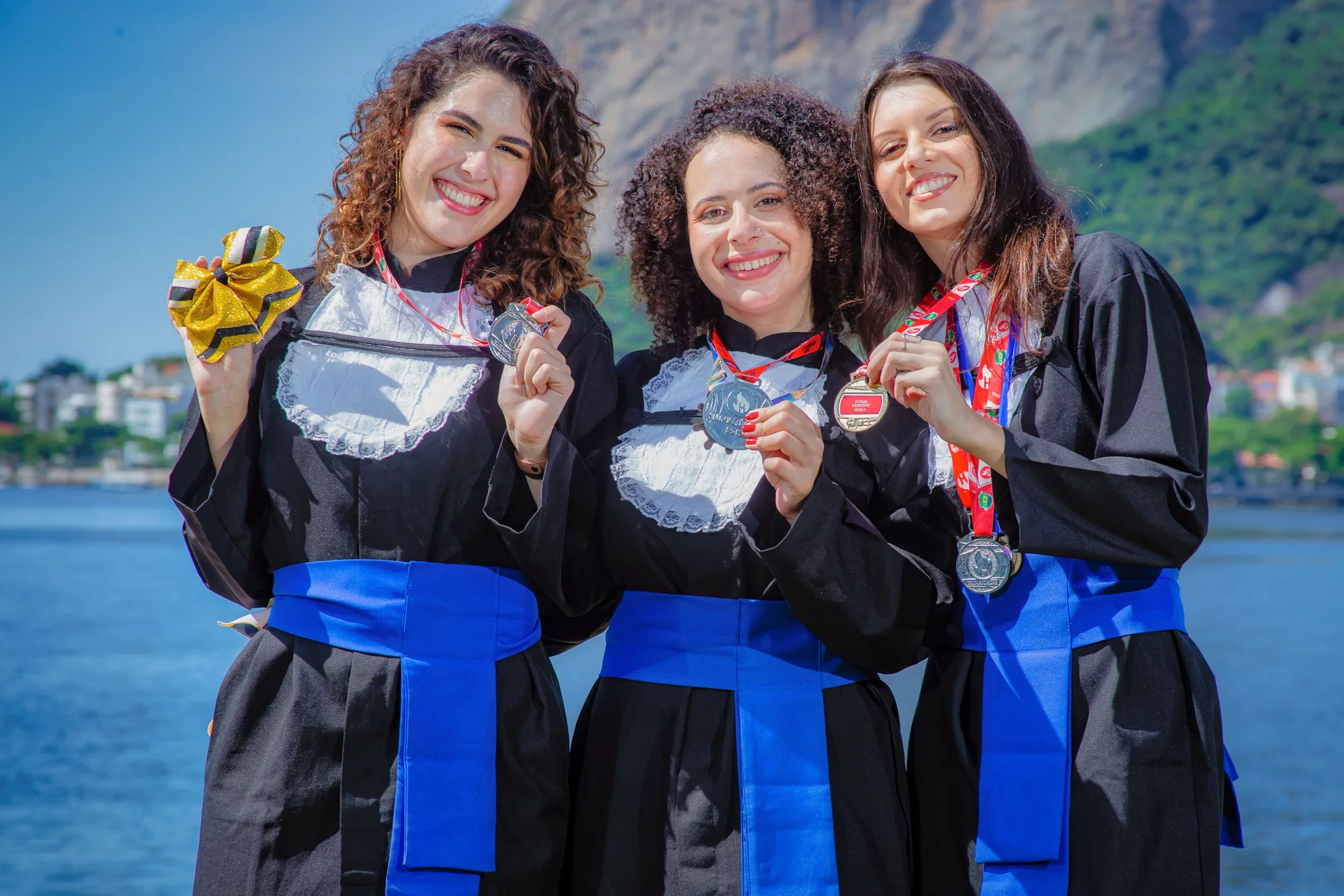 Três formandas de beca mostram as medalhas no Aterro do Flamengo