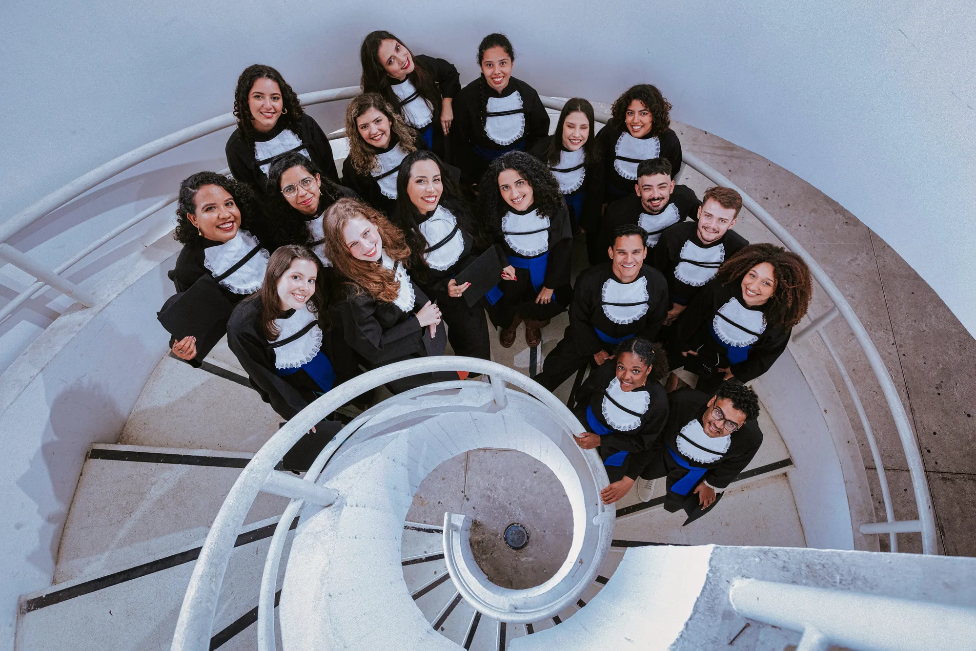 Turma de formandos de beca vista de cima na escada em espiral do Caminho Niemeyer