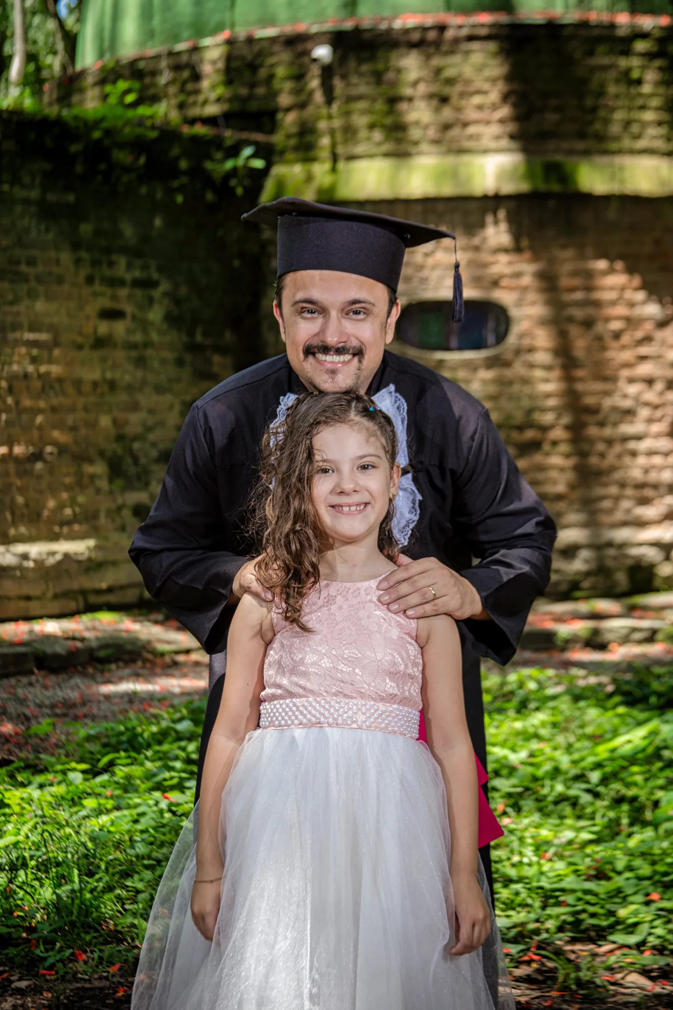 Formando de beca com a filha no colo em Paracambi