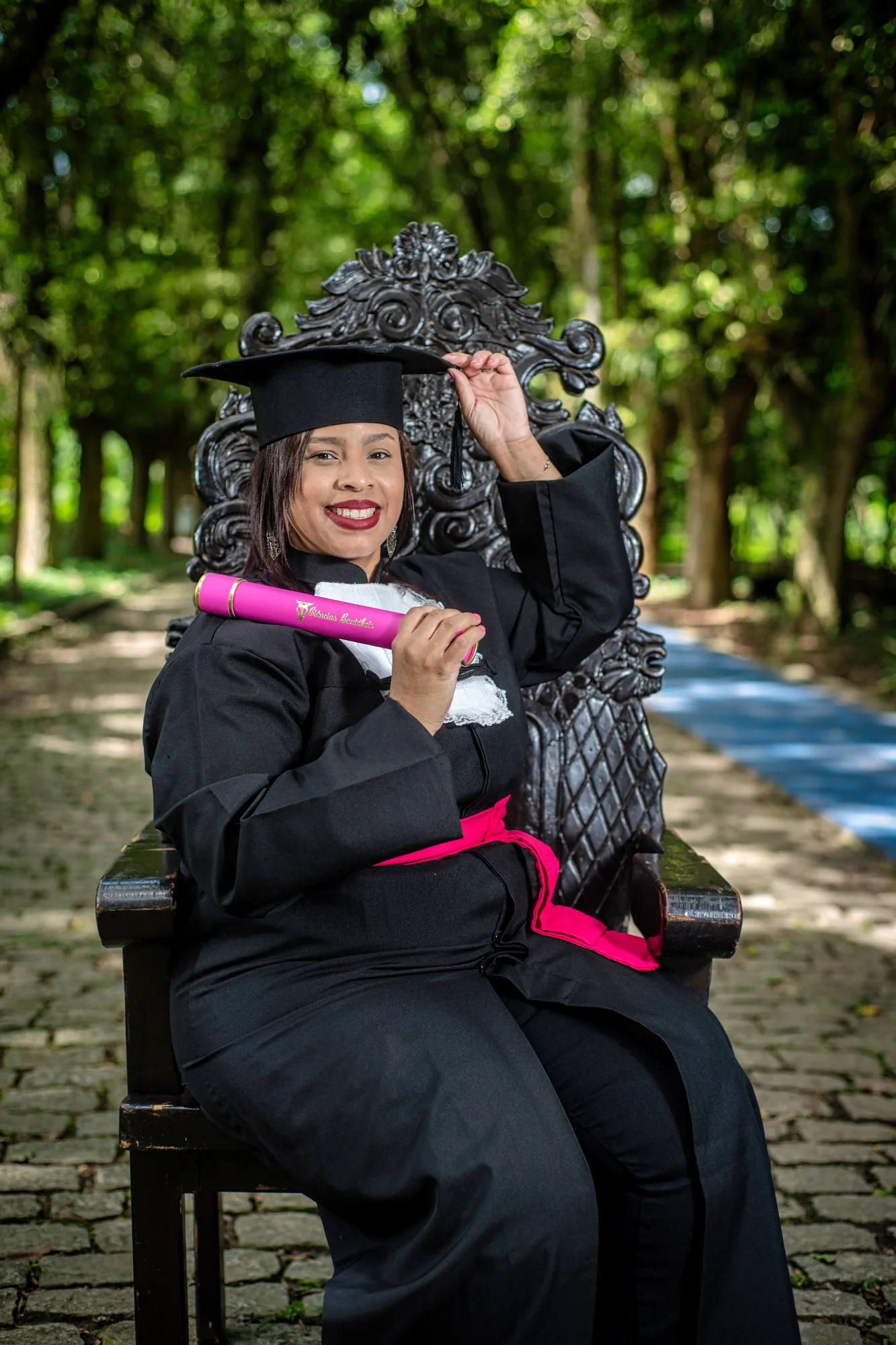 Formando de beca na cadeira entalhada na alameda de Paracambi