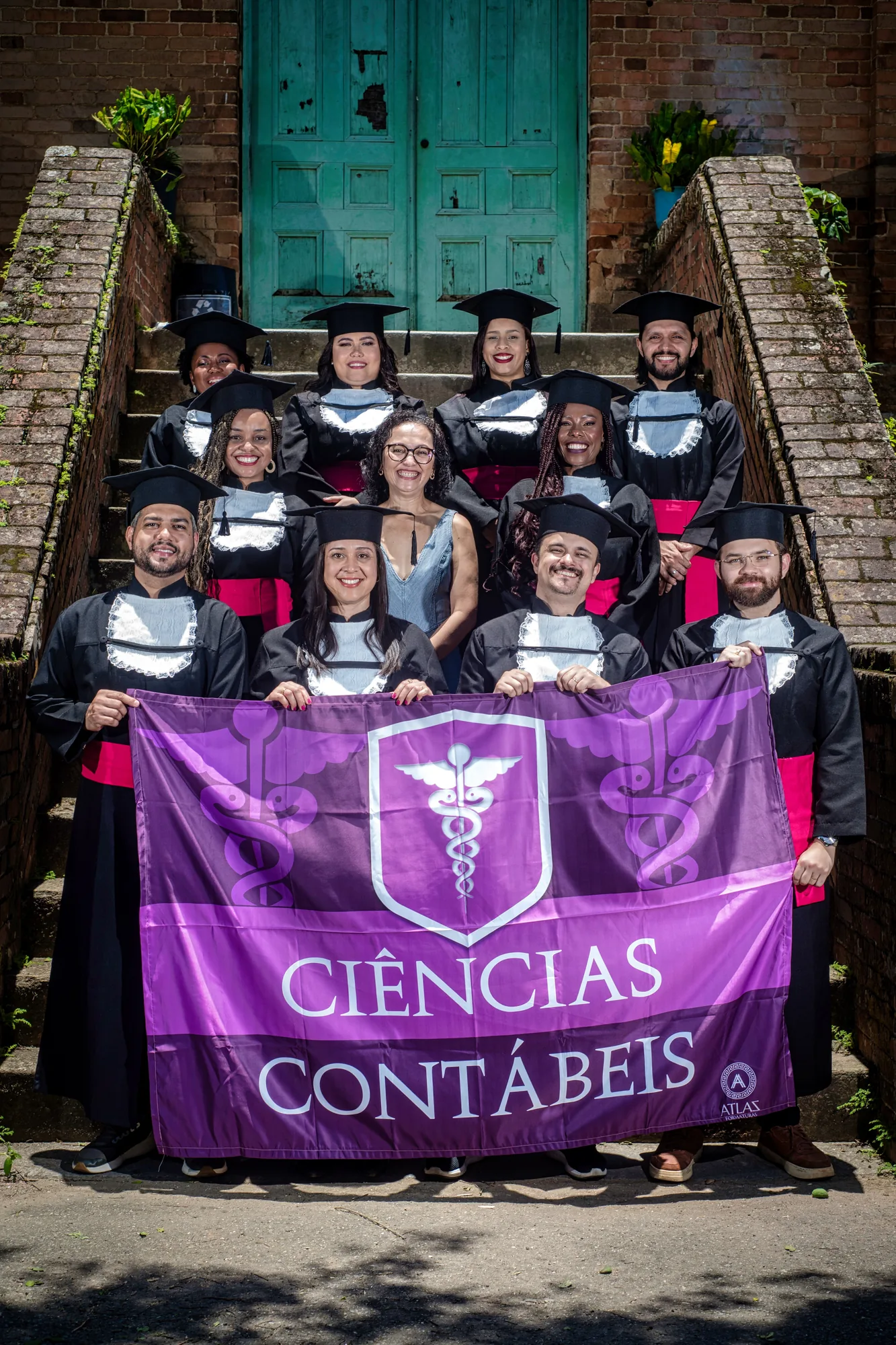 Turma de Ciências Contábeis com a bandeira do curso na escadaria, em Paracambi