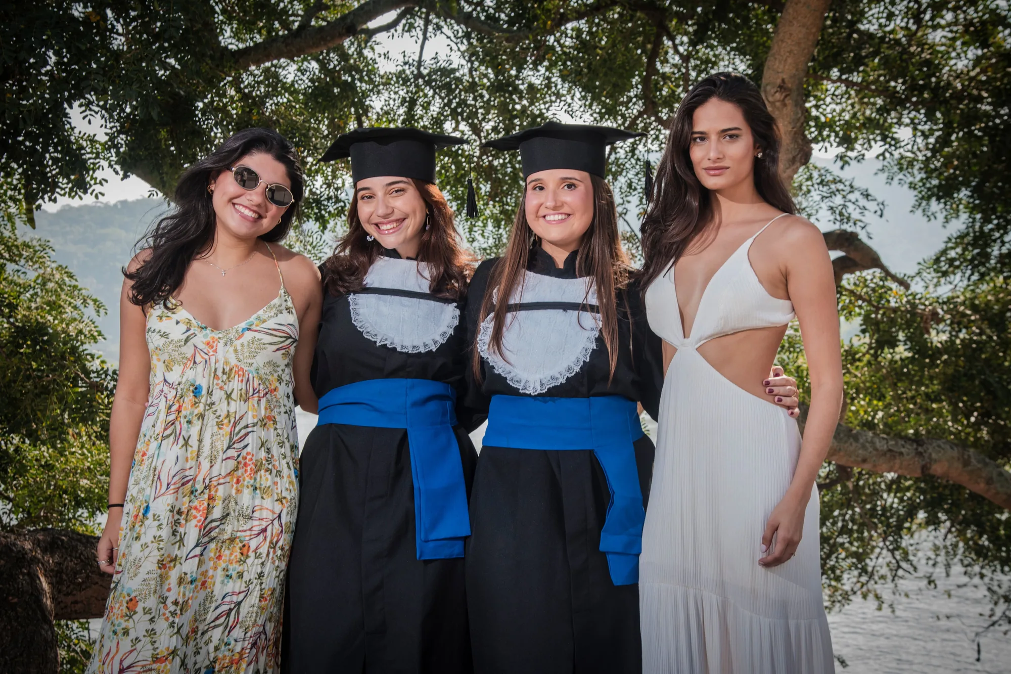 Duas formandas de beca abraçadas com duas amigas na Praça São Francisco