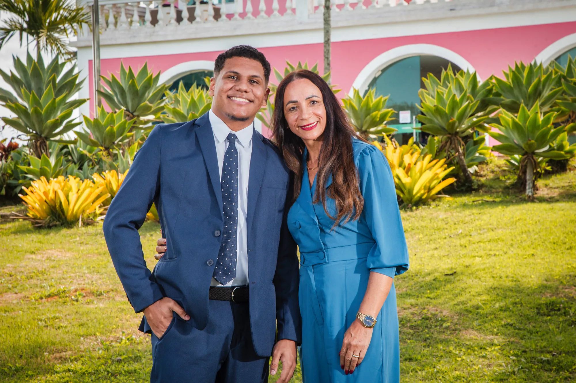 Estudante de terno ao lado da mãe no jardim do casarão rosa, em Rio das Ostras
