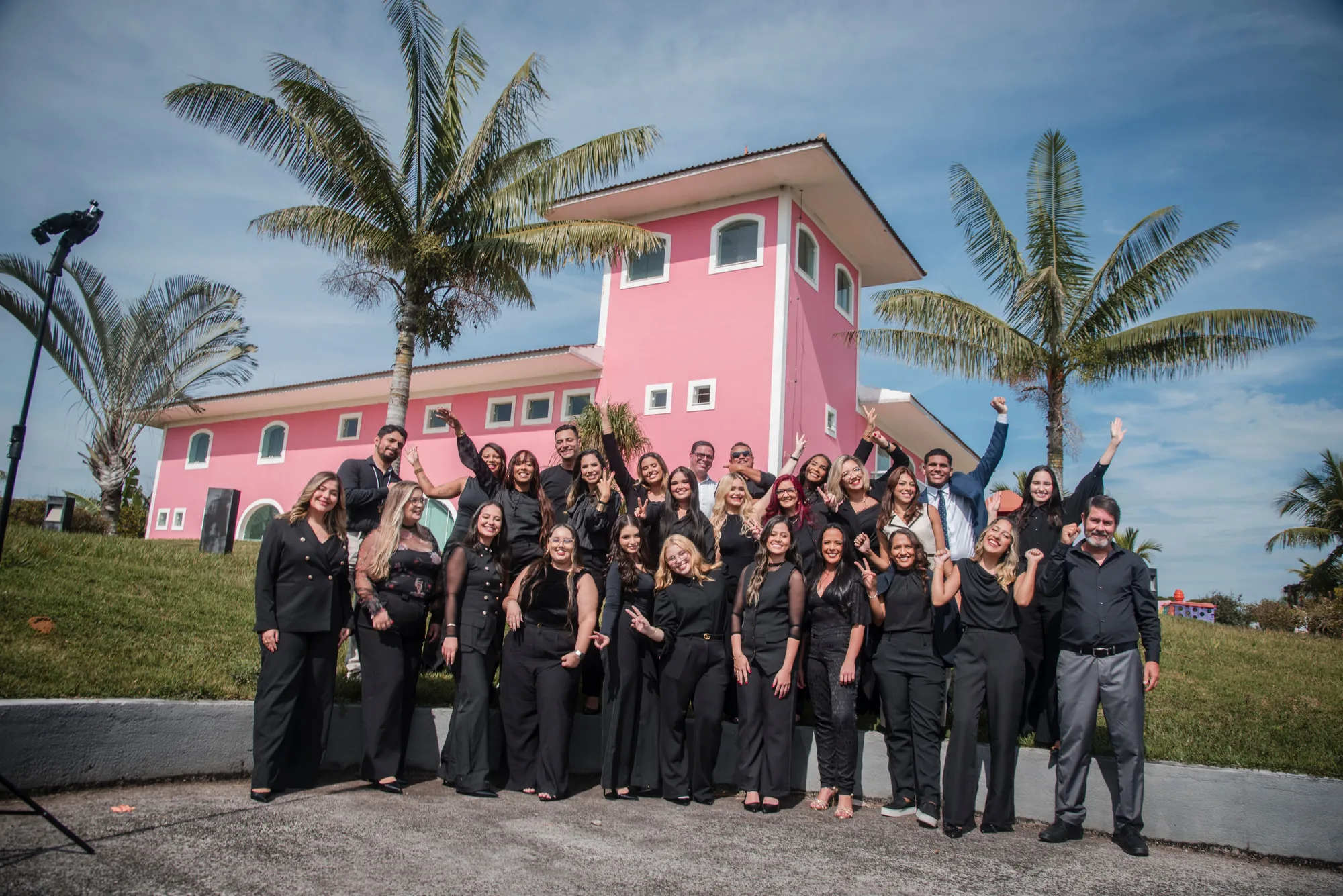 Turma vestida de preto comemora diante do casarão rosa, em Rio das Ostras
