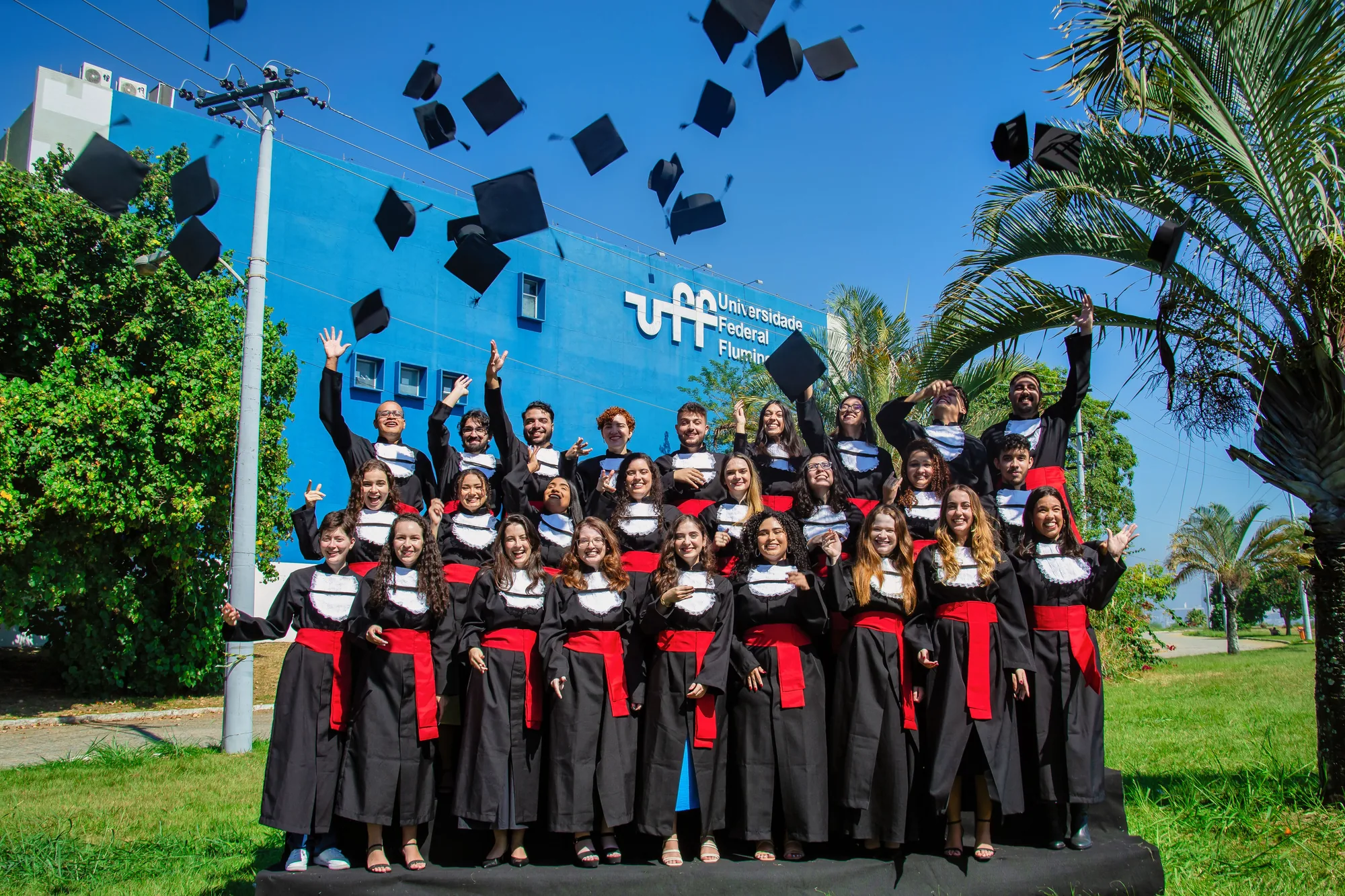 Turma de formandos joga os capelos para o alto diante do prédio da UFF, no Gragoatá