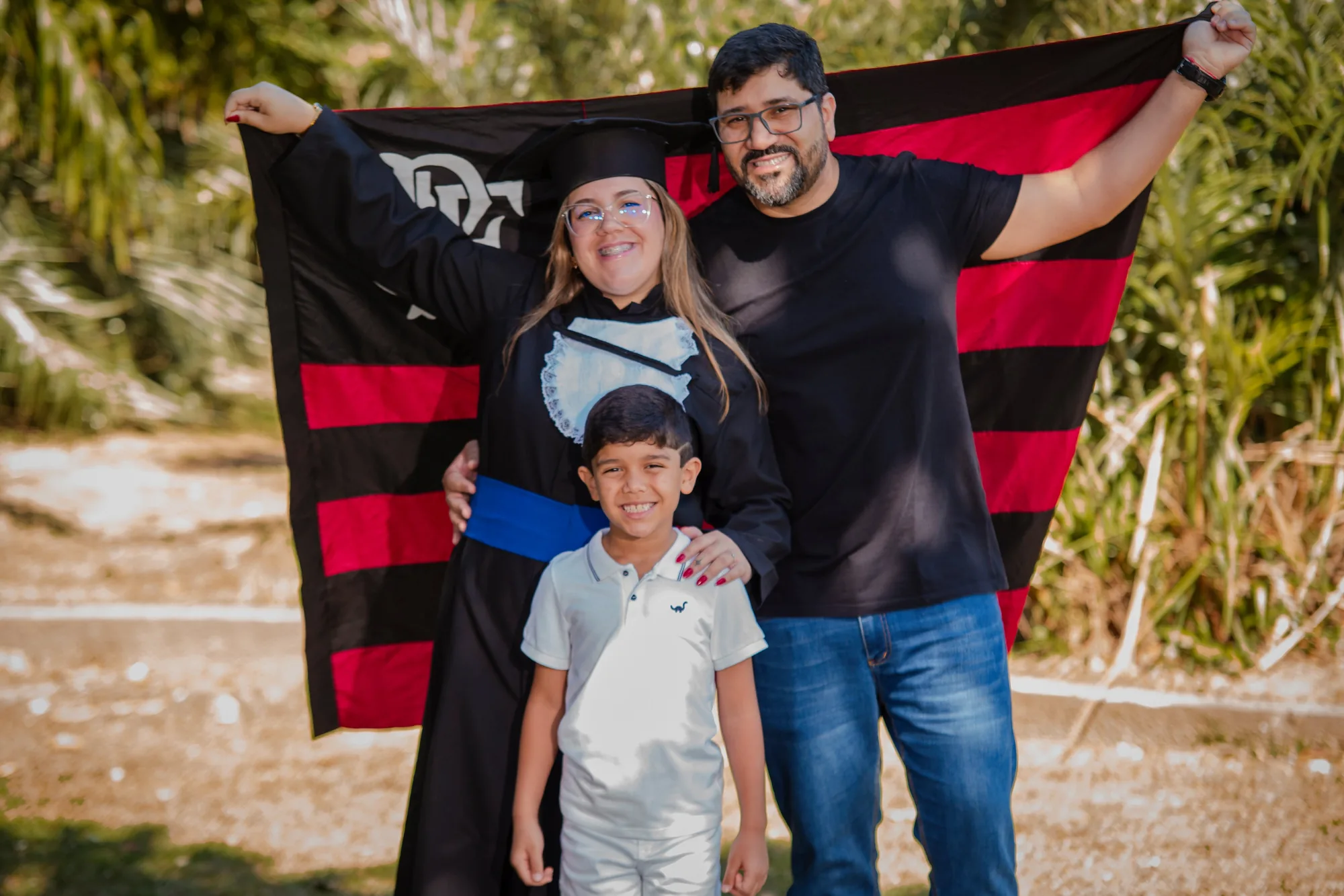 Formanda de beca com a família e a bandeira do time em Volta Redonda