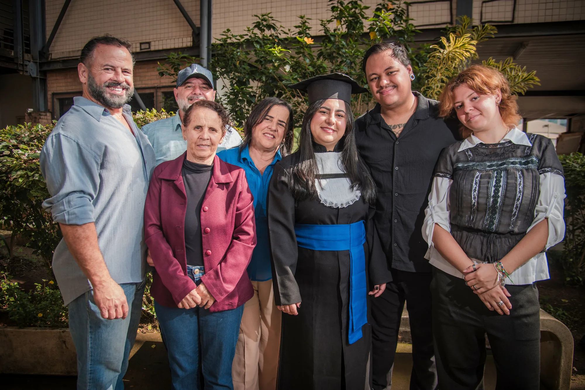 Formanda de beca reunida com a família no campus