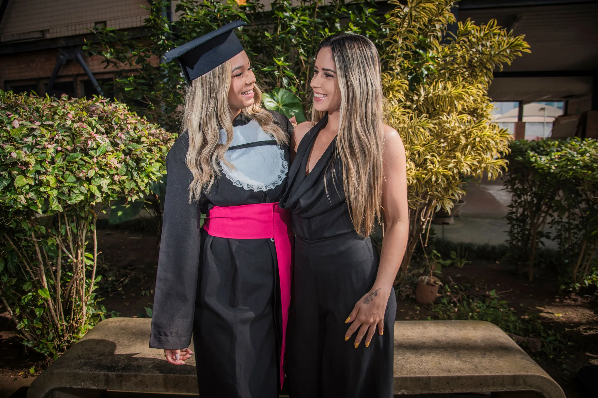 Formanda de beca sorri para a amiga no campus da UFF em Volta Redonda