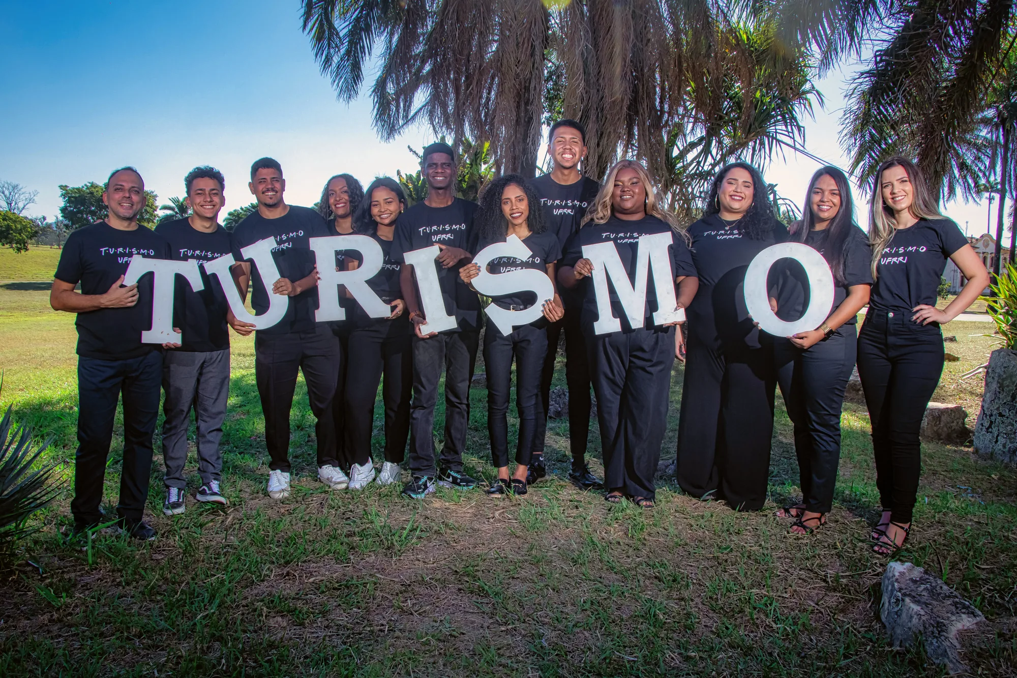 Turma de Turismo segura as letras do nome do curso no gramado da UFRRJ