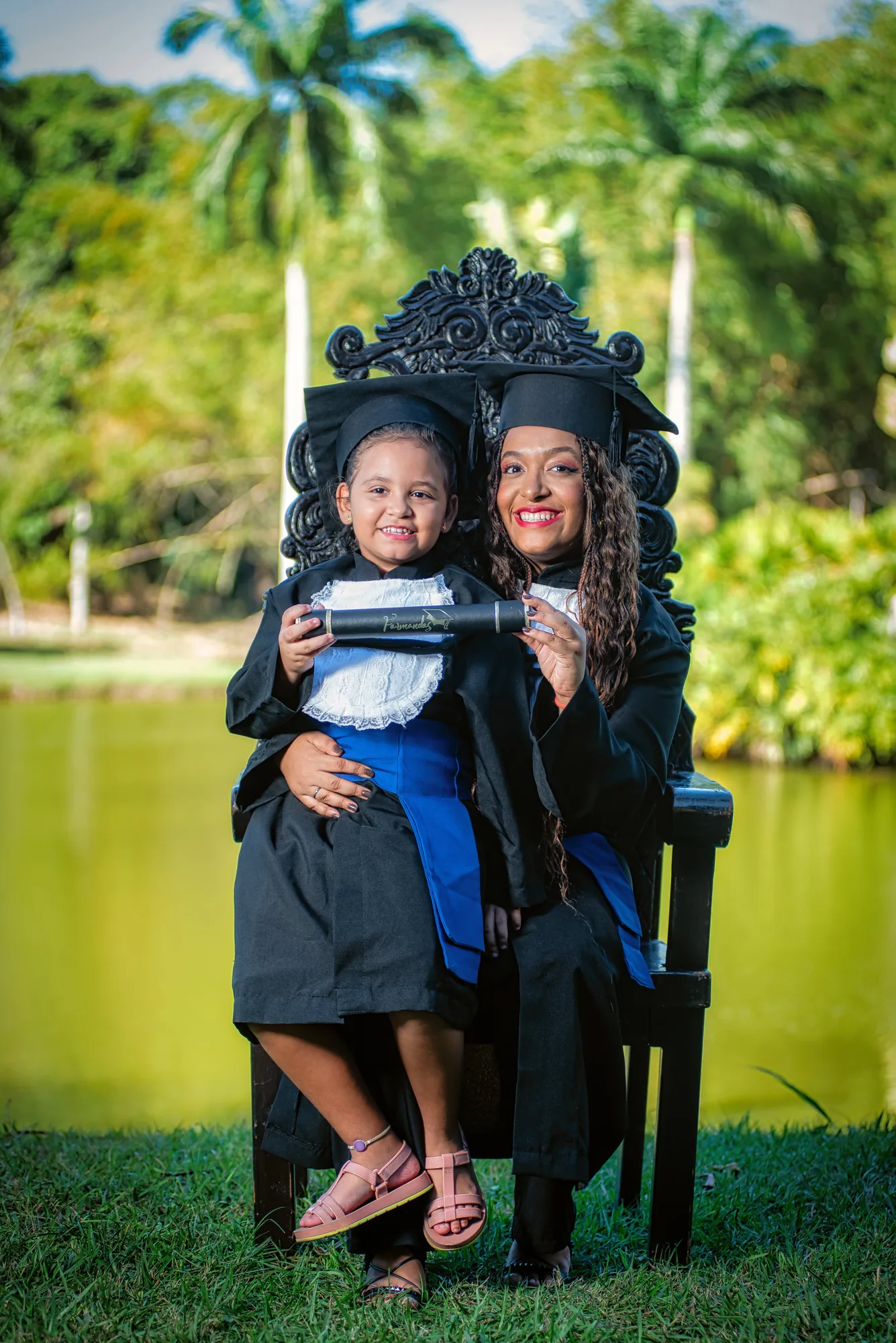 Formanda de beca na cadeira entalhada ao lado da mãe, na UFRRJ