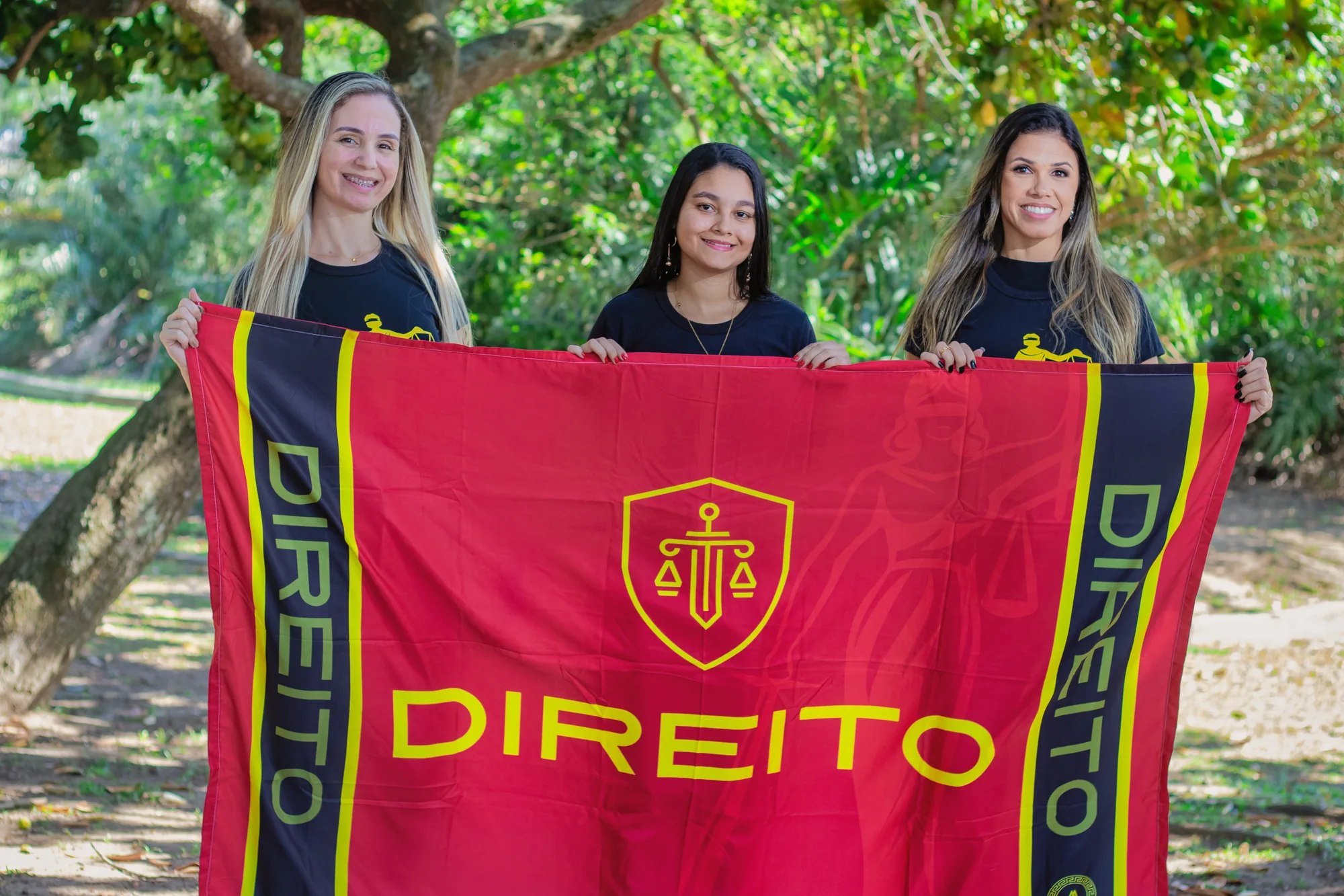 Três estudantes seguram a bandeira do curso de Direito na UFRRJ
