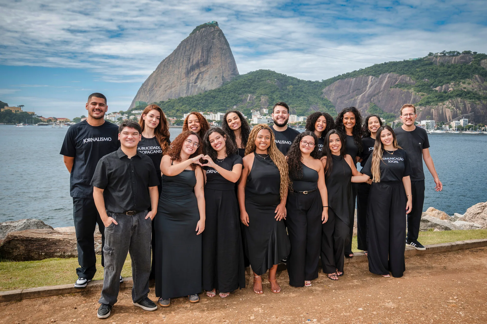 Turma vestida de preto em ensaio de meio de curso, com o Pão de Açúcar ao fundo